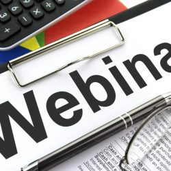 Clipboard with document saying webinar on messy desk